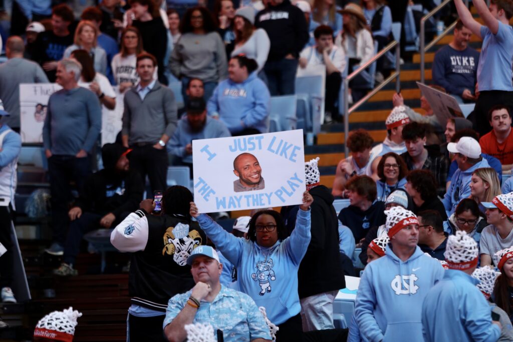 Fans in the stands of the Dean Smith Center holding handmade signs