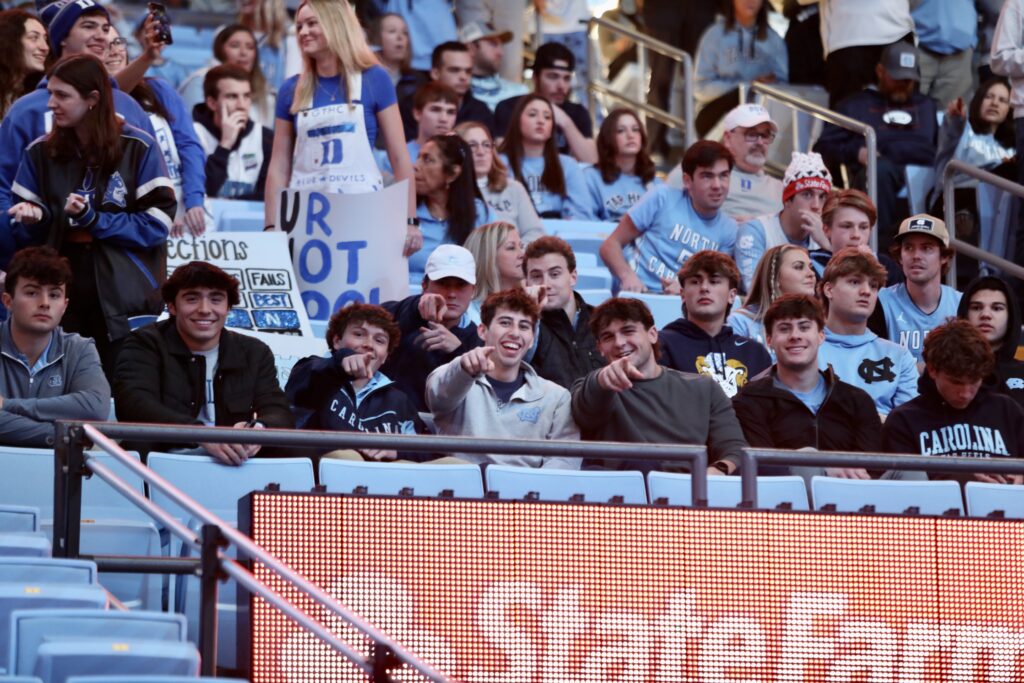Duke fans in the stands of the Dean Smith Center holding handmade signs